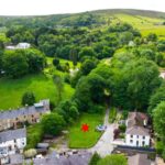 Lush woodland and charming cottages surrounding the 0.25-acre building plot on Astley Street, Darwen, with planning permission for luxury home