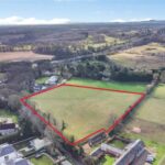 Gently sloping 3.74 acre grassland field with gated access and fencing in semi-rural Hartford, ideal for equestrian grazing or development